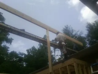 Carpenter setting a ridge beam over a new addition frame — Ice Dam Removal by Roofing Brothers in West Kingston