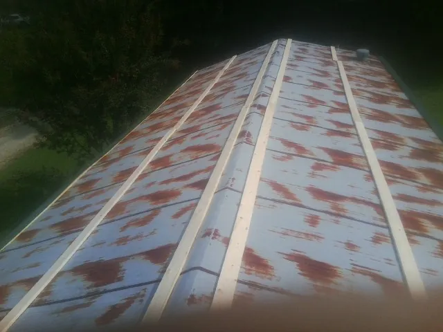 Rusted metal roof panels with new wood purlins before replacement — Storm Damage Roof Repair in West Kingston by Roofing Brothers