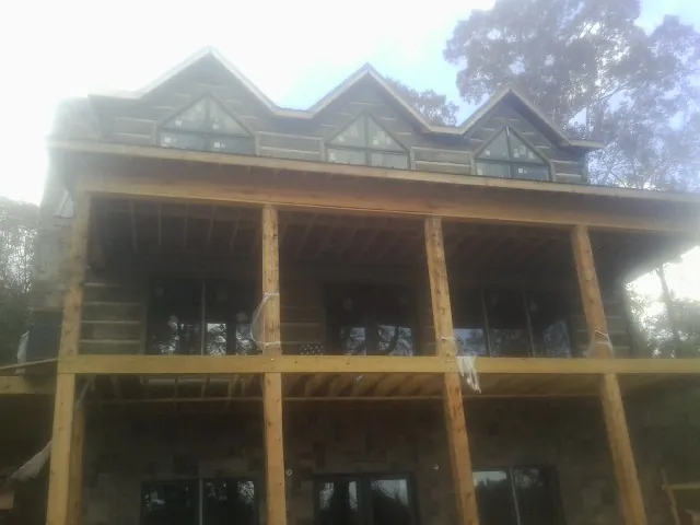 Dormers and porch framing on a large log home under construction — Roof Coating work by our crew in West Kingston