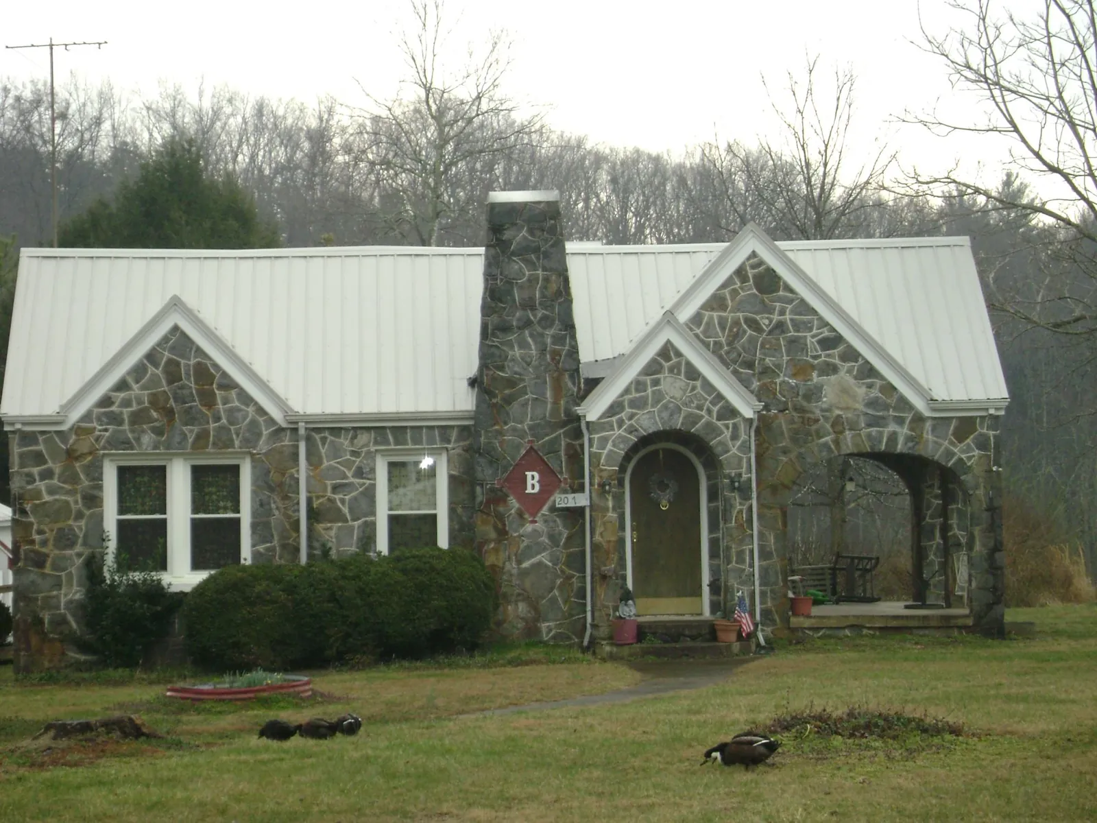White metal roof on a stone cottage with steep gables in West Kingston