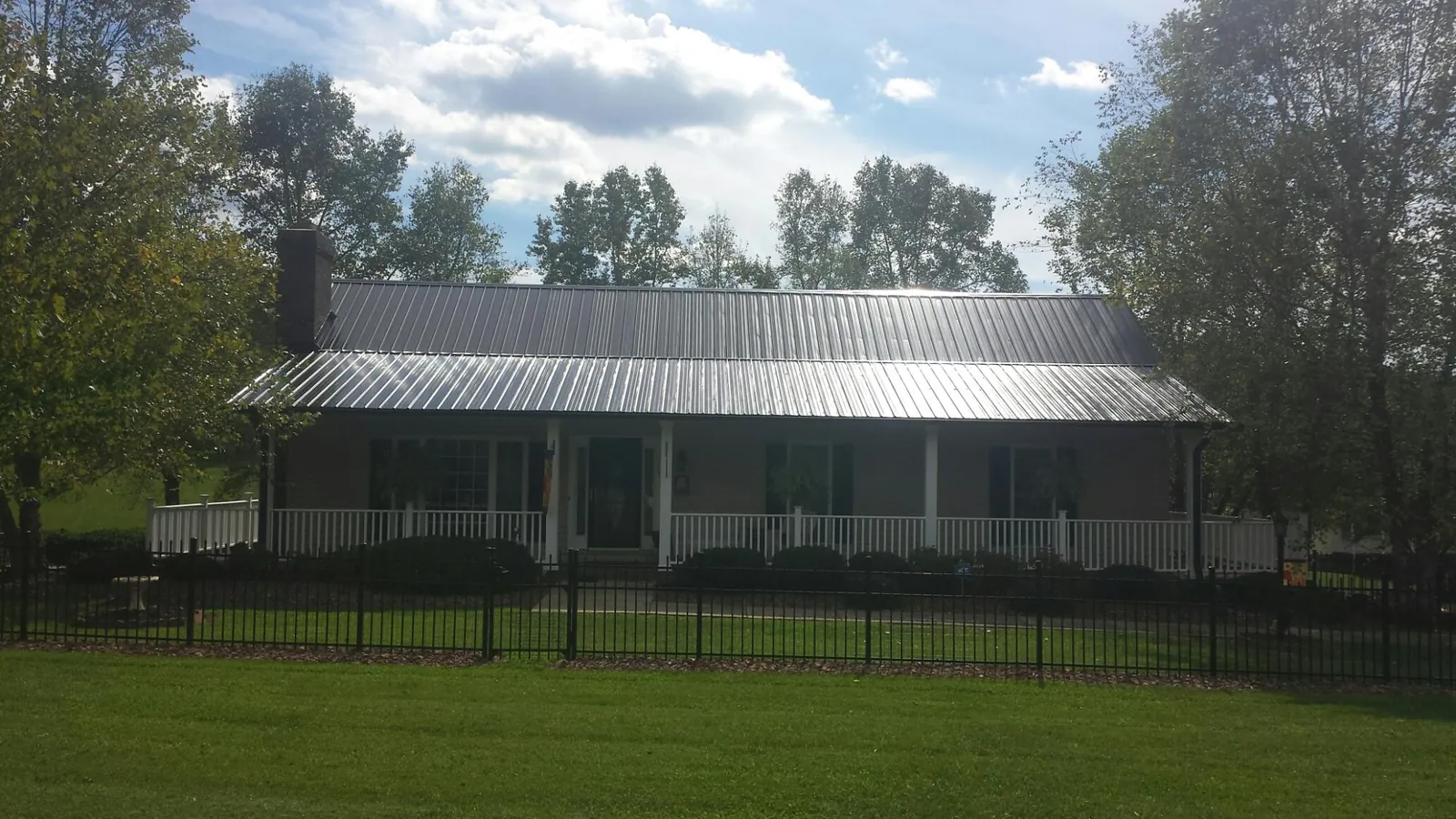 Gray metal roof on a brick ranch with a full width front porch — Gutter Guard Installation work by our crew in West Kingston