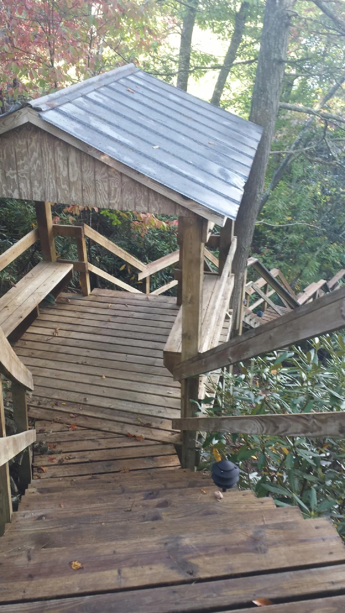 Metal roofed shelter over wooden steps on a wooded walkway — Skylight Repair & Installation work by our crew in West Kingston