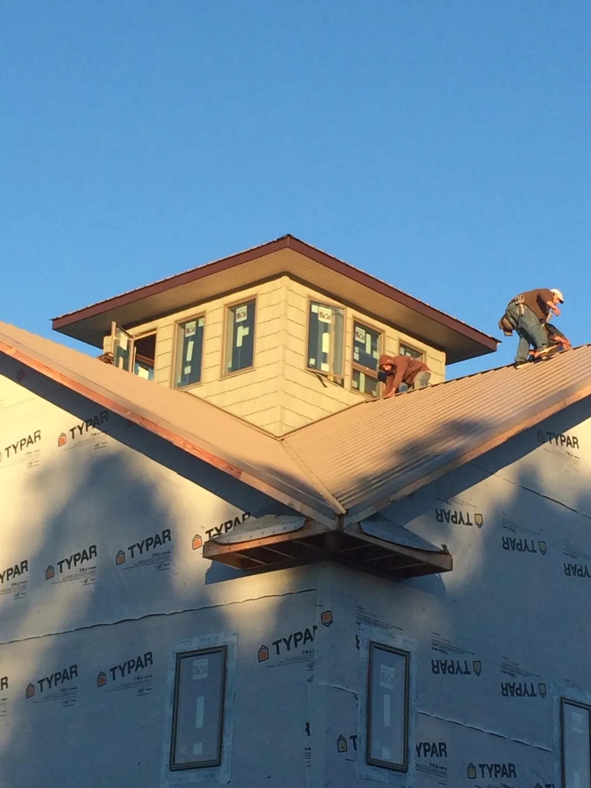 Roofers working around a rooftop cupola on a new metal roof at sunset — Roof Waterproofing in West Kingston by Roofing Brothers